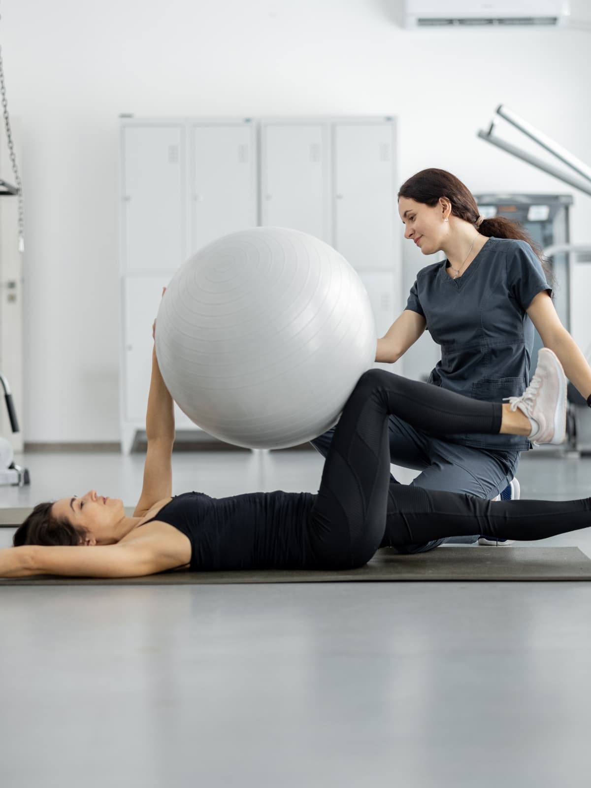 Physiotherapist helping a person with rehabilitation exercises on a gym floor