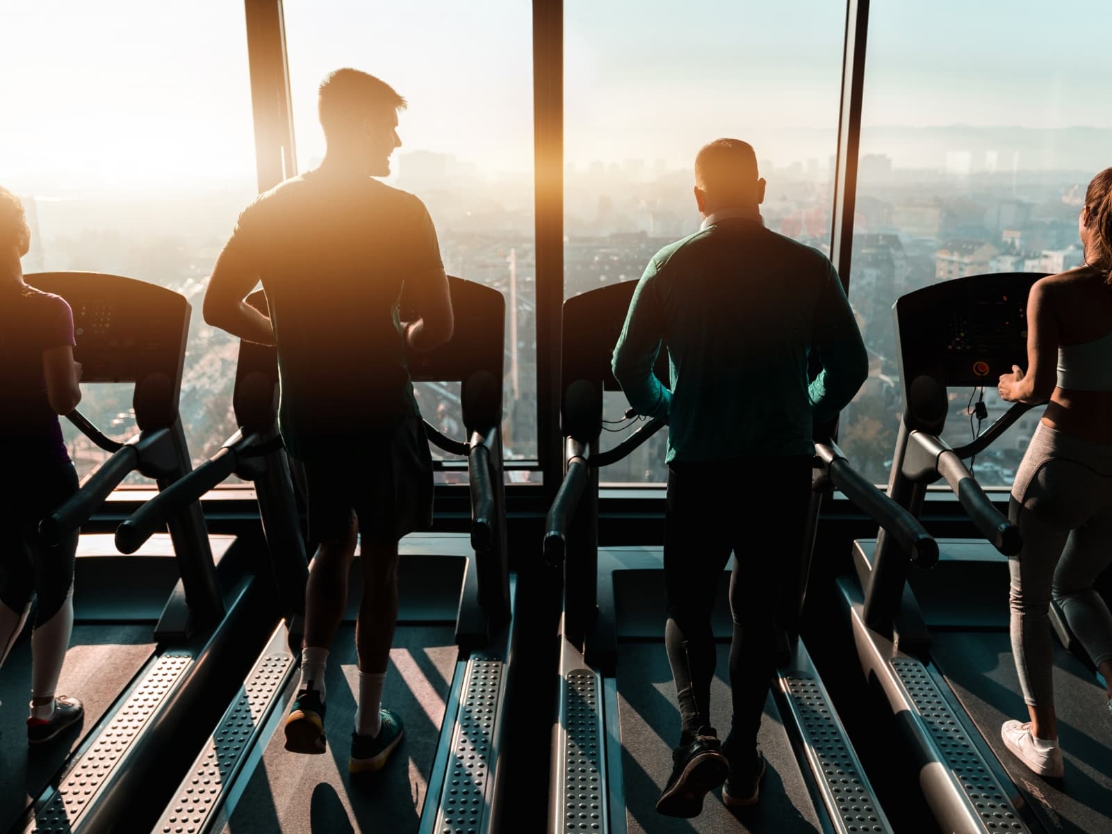People running on a treadmill towards the windows, sunrise over the city